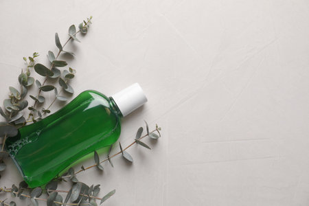 Fresh mouthwash in bottle and eucalyptus branches on light background, top view. Space for textの写真素材
