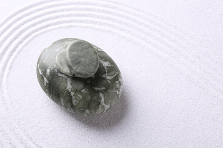 Zen garden stones on white sand with pattern, top view. Space for textの写真素材
