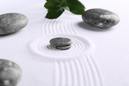 Zen concept. Stones, leaves and pattern on white sand, closeup