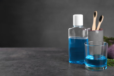 Fresh mouthwash in glass and bottle on dark textured table, closeup. Space for textの写真素材