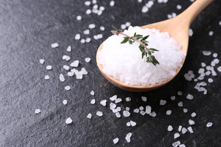 Salt with fresh thyme on dark gray textured table, closeup. Space for textの写真素材