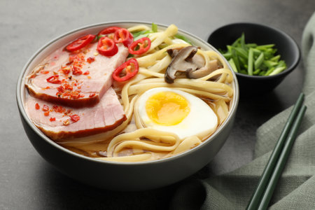 Delicious ramen in bowl and chopsticks on gray table. Noodle soupの写真素材