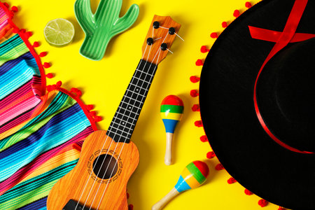 Flat lay composition with black Flamenco hat, poncho, ukulele and maracas on yellow tableの写真素材