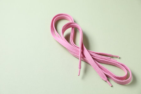 Stylish pink shoe laces on light olive background, closeup. Space for textの写真素材