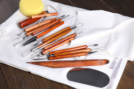 Set of different clay crafting tools on wooden table, closeup