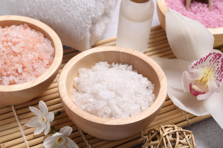 Different types of sea salt and flowers on light table, closeup. Spa productsの写真素材