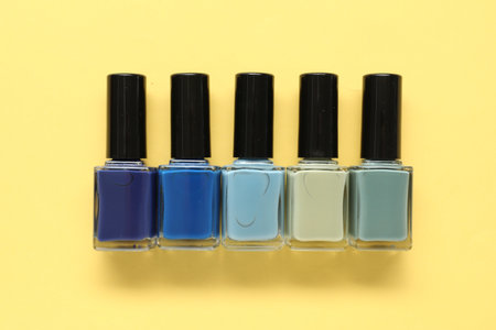 Bright nail polishes in bottles on yellow background, flat layの写真素材
