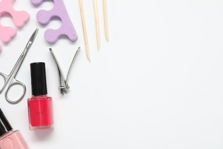 Nail polishes and set of pedicure tools on white background, flat lay. Space for textの写真素材