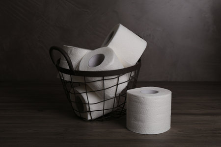 Soft toilet paper rolls in metal basket on wooden tableの写真素材