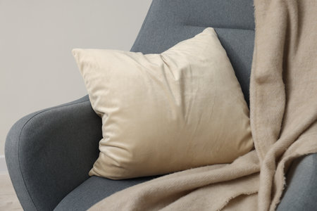 Soft pillow and blanket on armchair near light gray wallの写真素材