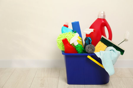 Different cleaning products in bucket on floor indoors, space for textの写真素材
