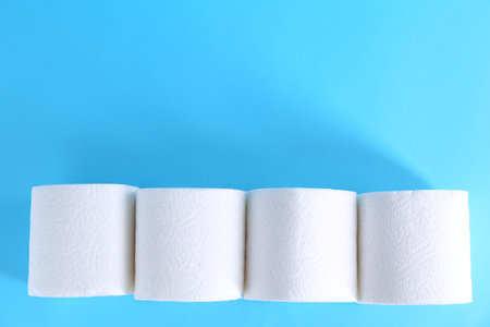 Soft toilet paper rolls on light blue background, flat lay. Space for textの写真素材