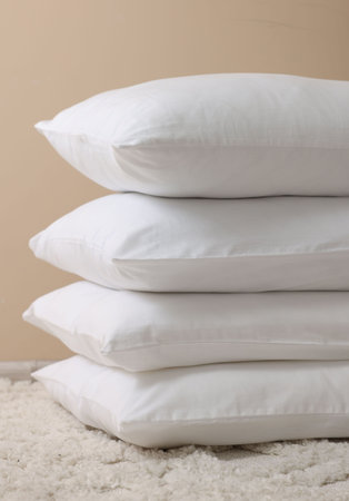 Stack of soft white pillows near beige wall indoorsの写真素材