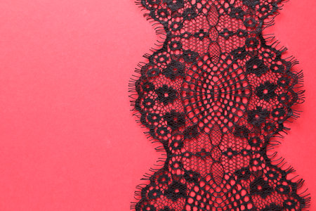 Black lace on red background, top view. Space for textの写真素材