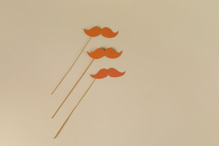 Fake paper mustaches party props on beige background, flat lay. Space for textの写真素材