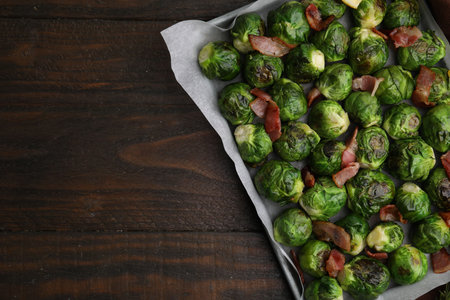 Delicious roasted Brussels sprouts and bacon in baking dish on wooden table, top view. Space for textの写真素材