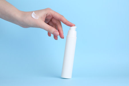Woman with cream on light blue background, closeupの写真素材