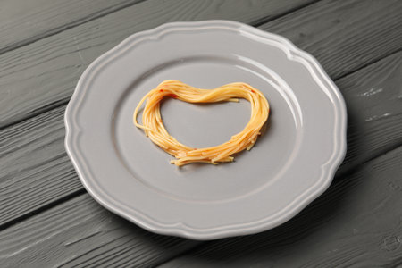 Heart made with spaghetti on gray wooden tableの写真素材