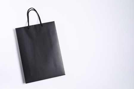 One black paper shopping bag on white background, top view. Space for textの写真素材