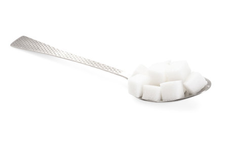 Sugar cubes in metal spoon isolated on whiteの写真素材