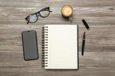 Flat lay composition with notebook and smartphone on wooden table