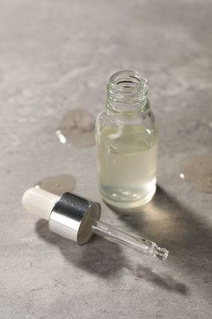Pipette and bottle of moisturizing serum on gray textured background
