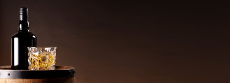 Whiskey in glass and bottle on wooden barrel against brown background, space for text. Banner designの写真素材