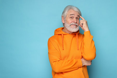 Senior man with mustache on light blue background, space for textの写真素材