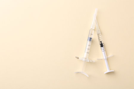 Injection cosmetology. Two medical syringes on beige background, top view. Space for textの写真素材