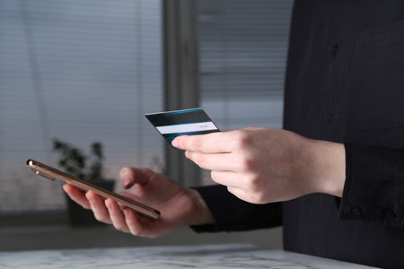 Online payment. Woman with smartphone and credit card at white marble table indoors, closeupの写真素材