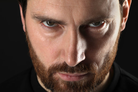 Evil eye. Man with scary eyes on black background, closeupの写真素材