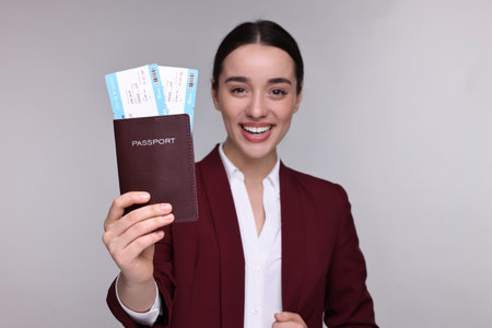 Smiling businesswoman showing passport and tickets on gray background, selective focusの写真素材