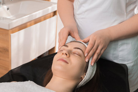 Cosmetologist making face massage to client in clinic, closeupの写真素材