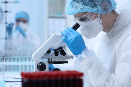 Scientist working with samples and microscope in laboratory
