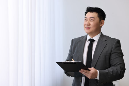 Portrait of happy notary with clipboard indoors, space for textの写真素材