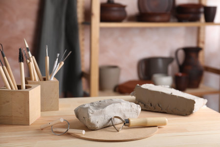 Clay and set of modeling tools on wooden table in workshopの写真素材