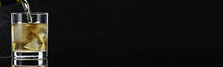 Pouring whiskey into glass on black background, closeup. Banner design with space for textの写真素材