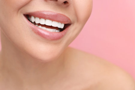 Woman with beautiful lips smiling on pink background, closeupの写真素材