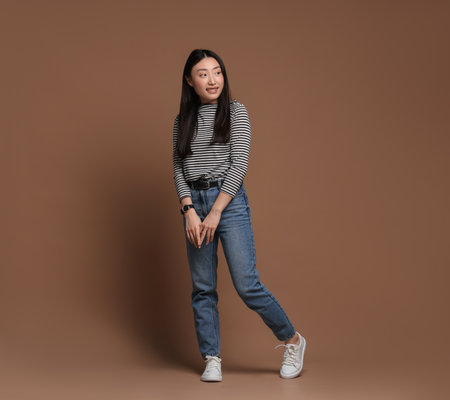 Full length portrait of smiling woman on brown background. Space for textの写真素材