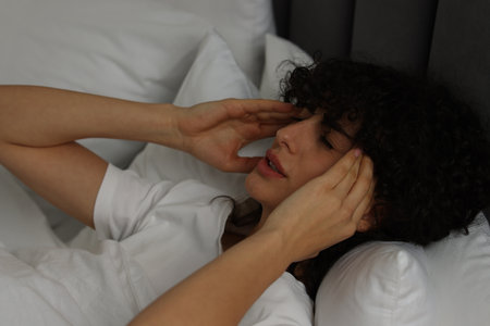 Young woman suffering from headache in bed at nightの写真素材