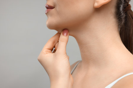 Woman touching her chin on gray background, closeup