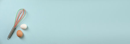 Whisk and eggs on light blue background, flat lay. Banner design with space for text