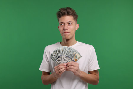 Handsome man with dollar banknotes on green backgroundの写真素材