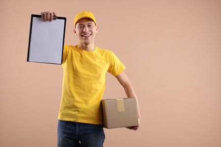 Happy courier with parcel and clipboard on beige background. Space for text