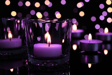 Burning violet candle on black background, closeup. Funeral attributesの写真素材