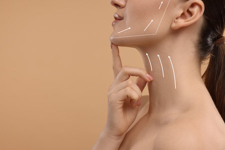 Woman with perfect skin after cosmetic treatment on beige background, space for text. Lifting arrows...