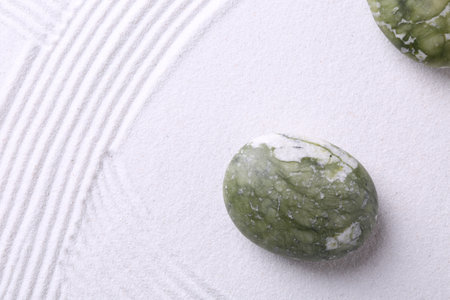 Stones on sand with pattern, flat lay. Zen concept