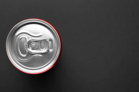 Energy drink in can on black background, top view. Space for text