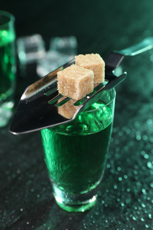 Absinthe in shot glass, spoon and brown sugar cubes on gray table, closeup. Alcoholic drinkの写真素材