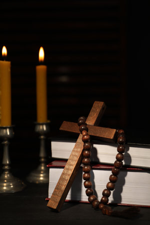 Church candles, Bible, rosary beads and cross on wooden tableの写真素材
